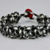 black and white camouflage paracord bracelet with red button, picture of a black and white camouflage paracord bracelet with red button fastener in the back on a white background