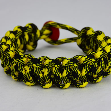 black and yellow camouflage paracord bracelet with red button in the back, picture of a black and yellow camouflage paracord bracelet with red button fastener in the back on a white background