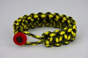 black and yellow camouflage paracord bracelet unity band with red button, picture of a black and yellow camouflage paracord bracelet unity band with red button fastener in the front on a white background