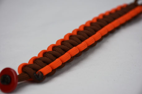 brown orange and brown paracord bracelet unity band with red button in the corner, brown orange and brown paracord bracelet with red button fastener in the front corner on a white background