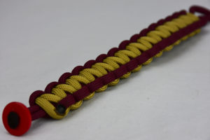 burgundy burgundy and gold paracord bracelet with red button in the corner, picture of a burgundy burgundy and gold paracord bracelet with red button fastener in the bottom corner