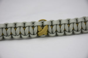 gold and grey pediatric cancer support paracord bracelet with gold ribbon in the center