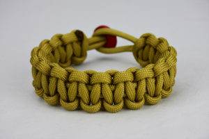 gold paracord bracelet unity band with red button, picture of a gold paracord bracelet unity band with a red button fastener in the back on a white background