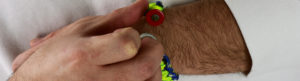 how to size a paracord bracelet, picture of a man trying to put a unity band paracord bracelet on to see if the size is right