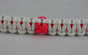 pink and white breast cancer support paracord bracelet with pink ribbon in the center