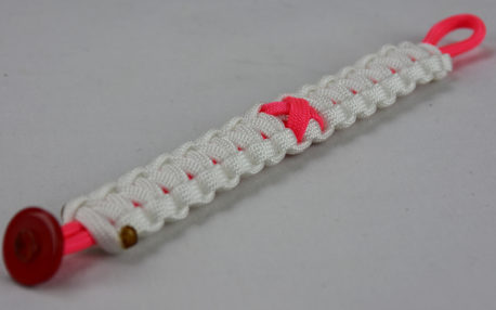 pink and white breast cancer support paracord bracelet with red button fastener in the corner and pink ribbon