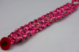 pink camouflage paracord bracelet unity band with red button in the corner, picture of a pink camouflage paracord bracelet unity band with red button fastener in the front corner on a white background