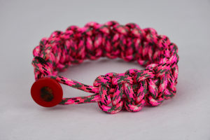pink camouflage paracord bracelet unity band with red button on front, picture of a pink camouflage paracord bracelet with red button fastener on the front and a white background
