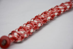 red and white camouflage paracord bracelet unity band with red button in the corner, picture of a red and white camouflage paracord bracelet unity band with red button fastener in the corner on a white background