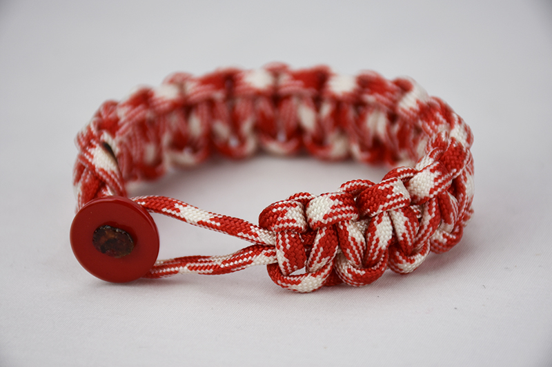 red and white camouflage paracord bracelet with red button in front, picture of a red and white camouflage paracord bracelet unity band with red button fastener in the front on a white background