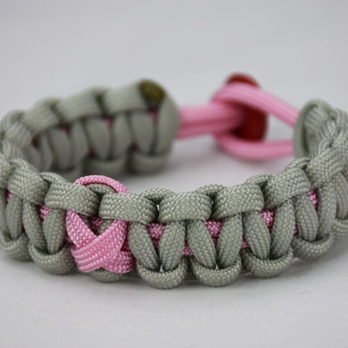 soft pink and grey breast cancer support paracord bracelet with pink ribbon and red button, picture of a unity band soft pink and grey breast cancer support paracord bracelet with a pink ribbon in the center and a red button fastener