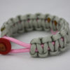 soft pink and grey breast cancer support paracord bracelet with a pink ribbon and red button, picture of a soft pink and grey breast cancer support paracord bracelet unity band with a red button in the front and pink ribbon in the back