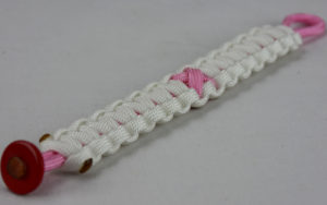soft pink and white breast cancer support paracord bracelet with red button in the corner and soft pink ribbon