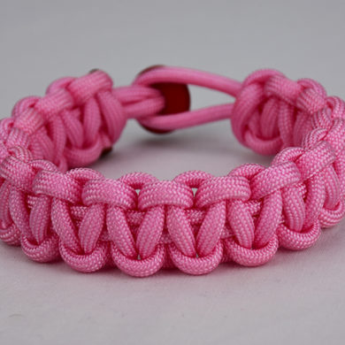 soft pink paracord bracelet unity band with red button, picture of a soft pink paracord bracelet with red button fastener in the back on a white background