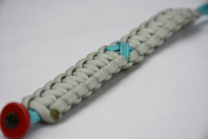 teal and grey ptsd support paracord bracelet with red button in the front corner and teal support ptsd ribbon