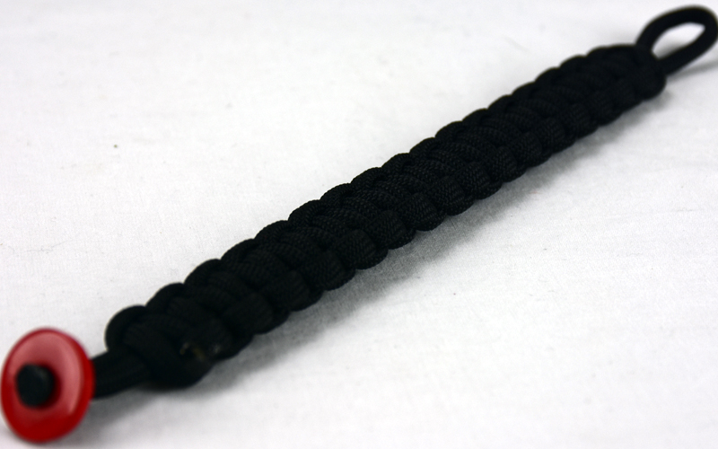 black paracord bracelet with red button in the corner