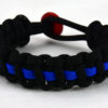 black paracord bracelet with blue line and a red button fastener in the back