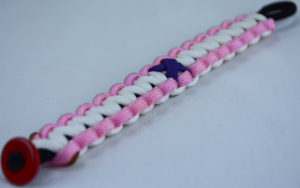 black soft pink and white alzheimers support paracord bracelet with red button fastener in the corner and purple ribbon