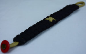 gold and black pediatric cancer support paracord bracelet with red button fastener in the corner and gold ribbon