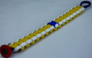 navy blue white and yellow anti bullying paracord bracelet with red button in the bottom corner and blue ribbon