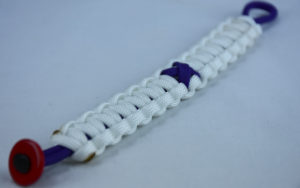 purple and white alzheimers support paracord bracelet with red button fastener in the bottom corner and purple ribbon