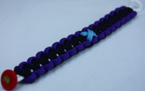 white purple and black prostate cancer support paracord bracelet with red button in the bottom corner and tarheel blue ribbon